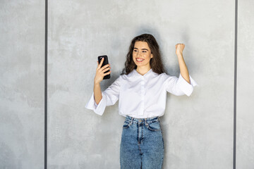 Excited young woman amazed by unbelievable shopping mobile app sale message looking at smartphone isolated on white background