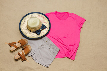 Sand beach texture background. Mockup pink summer t-shirt outfit copy space. Blank template woman shirt Top view. Summertime accessories hat, jeans. Flat-lay closeup tshirt on seashore. Beachtime