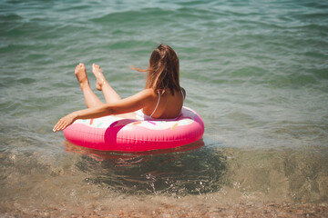 Young sexy woman in a slender body in a white swimsuit next to an inflatable mattress. Summer holidays. Rest on the sea. The concept of a healthy lifestyle.
The girl is resting on the sea. 