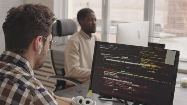 Stab shot of two male computer programmers coding on pc in modern office