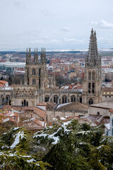 Obraz premium Paisaje de la Catedral de Burgos vista desde el mirador del castillo de la ciudad con todas las casa rodeándola bajo un cielo nublado.