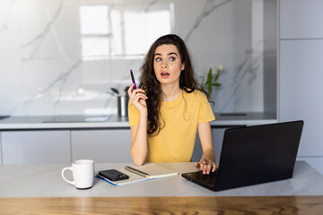 Freelancer is planning future and dreaming. Spahish woman is sitting in front of computer at home. Employee is working on project and thinking on ideas.