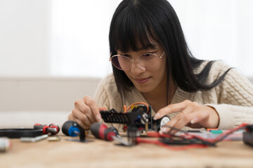 Young Asian female  learning toy robotics technology online with computer tablet. Young Asian woman building robotic toy car in classroom. Education and technology concept