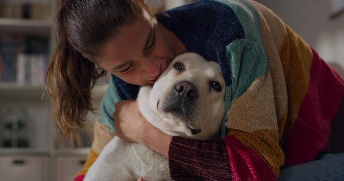 Portrait of Beautiful Young Woman Cuddles Her Adorable Labrador Retriever at Home. Girl Plays with Her Dog, Best Friend. She Pets and Scratches Super Happy Doggy, Have Fun in the Living Room