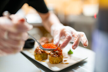 professional chef's hands making sushi roll in a restaurant kitchen