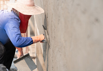Worker plastering cement on wall.