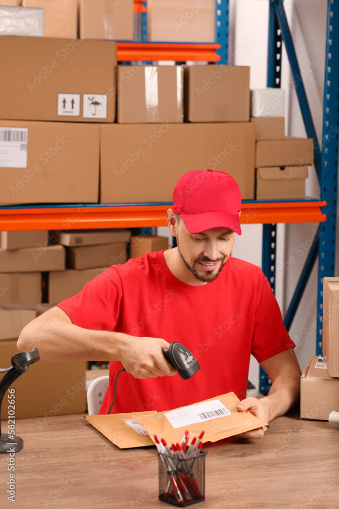 Wall mural Post office worker with scanner reading parcel barcode at counter indoors