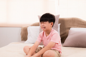 Asian adorable boy crying on bed because he didn't go out to play with his friends on holiday. young children making mistakenly crying in bedroom. son scolded by mother.