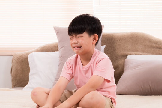 Asian adorable boy crying on bed because he didn't go out to play with his friends on holiday. young children making mistakenly crying in bedroom. son scolded by mother.