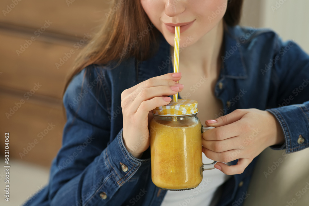 Wall mural Woman drinking delicious smoothie indoors, closeup view