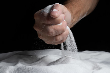 Sand through fingers on black background. Concept of the flow of life.