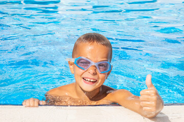 Smiling boy in a  in a pool. Boy with swimming goggles. Summer vacation concept. Childhood