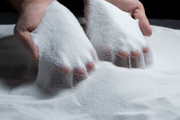 Sand through fingers on black background. Concept of the flow of life.