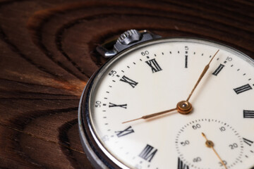 Old pocket watch on wooden background close up