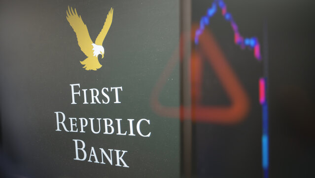 The First Republic Bank logo through a glass, with a blur alert sign reflection, a blur stocks chart on a screen, logo of first republic bank.