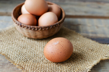 Chicken eggs in a wicker bowl on burlap on a wooden background. Rustic style. The concept of organic food. Selective focus. Horizontal orientation.