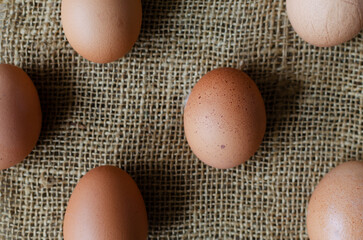 A lot of chicken eggs on burlap on a wooden background. Rustic style. The concept of organic food. Horizontal orientation. Top view.