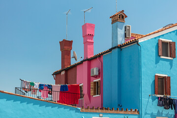 Brightly colored houses in Burano, Venice, Italy. Visitors see a range of colors, incl. vibrant blues, yellows, greens, and pinks, as they explore the island's winding streets and picturesque canals.