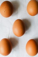 Five chicken eggs on a white tablecloth. Rustic style. The concept of organic food. Minimalism. Vertical orientation. Pattern.