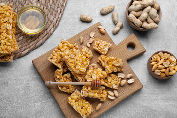 Delicious peanut kozinaki bars, nuts and honey on light gray textured table, flat lay