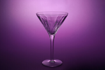 Elegant empty martini glass on purple background