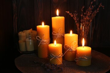 Beautiful burning beeswax candles and dried lavender flowers on table - obrazy, fototapety, plakaty