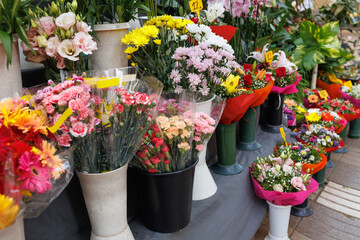 Fototapeta na wymiar Bouquets of Colorful Flowers inside their Vases outdoor in front of a Florist