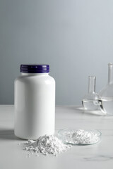 Calcium carbonate powder, jar and laboratory glassware on white marble table