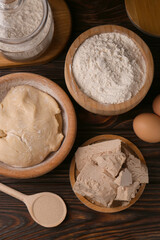 Different types of yeast, eggs, flour and dough on wooden table, flat lay