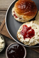 Freshly baked soda water scones with cranberry jam and butter on wooden table, flat lay