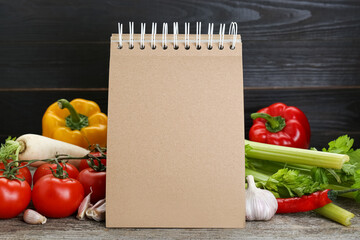 Blank recipe book and different ingredients on wooden table