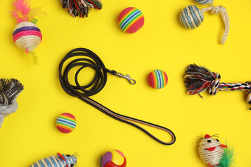 Flat lay composition with pet leash and toys on yellow background