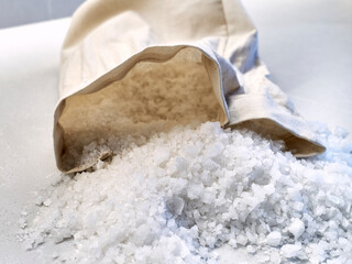          Front view of a small sack of salt spilled out on a kitchen counter          
