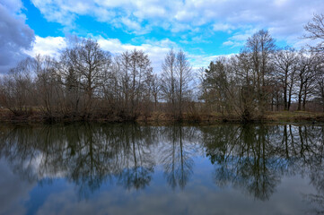 The reflection of trees in the mirror surface of the lake water of a mountain pond. Photo spring sketch. HDR style