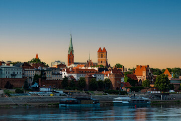 Obraz premium 04-07-2022: View of Old City of Torun. Vistula (Wisla) river against the backdrop of the historical buildings of the medieval city of Torun. Poland.