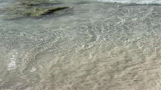 Sea ​​waves arriving on a golden sandy beach. The water is transparent