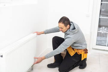 repairman using tools while installing or repairing heating radiator. plumber installing heating system in apartment. radiator installation, plumbing works and home renovation