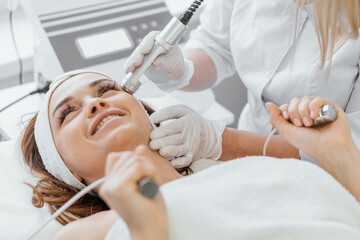 Electroporation without injection mesotherapy. Woman cosmetologist performs cosmetic procedure on...