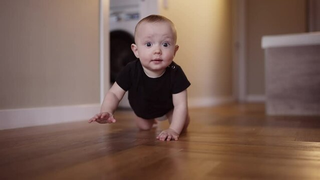 baby learns to crawl on the floor at home. happy family kindergarten kids concept. First steps, baby crawling front view . baby learns to crawl to explore the world around dream him