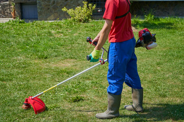 a man works with a brush cutter in the yard,gardener mows the grass in the spring with a brush cutter