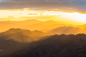 Obraz premium 日本 京都府宮津市にある成相山パノラマ展望台から夕焼け空と山々を照らす光芒