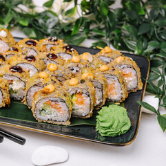 Served warm sushi with ginger and wasabi on a black stone plate.