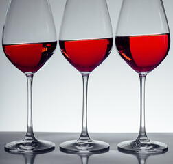 Series of three glasses of wine on gray background