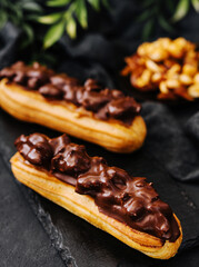 Two eclairs with dark chocolate on black board