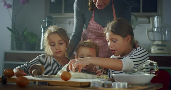 Portrait of Woman and her Children in the Kitchen Baking Together. Mother Teaching her Little Kids How to Make Cookies. Siblings Helping their Mother with Cooking. Happy Childhood Memories