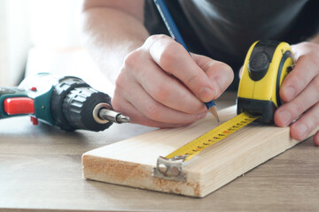 Carpenter hand measuring tape with pen in construction site. Making measurements with measuring...