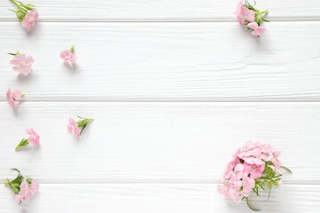 Small pink flowers on white wooden background