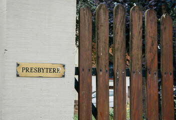 Obraz premium A wooden fence, adorned with a presbytery signage in western script, stands silently in the day communicating security and warning through its text.