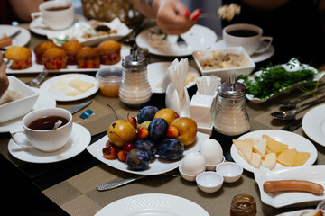 Buffet: fruit, plums, plates, coffee, boiled egg, cheese, salt shaker, sausages, served. Breakfast for tourists in the restaurant, delicious food