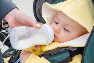 Baby boy contentedly drinks milk from a bottle.